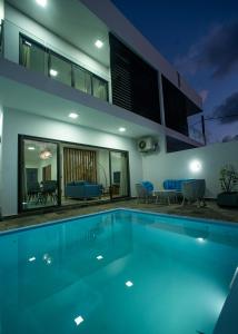 una piscina frente a una casa por la noche en Ocean Blue Villa, Flic-en-Flac, en Flic en Flac