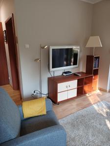 a living room with a blue couch and a tv at Apartament blisko plaży in Pobierowo