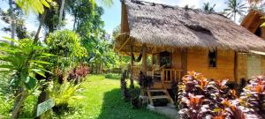 a house with a thatched roof in a garden at Second Home Bungalows in Tetebatu