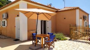 een tafel en stoelen met een parasol voor een huis bij NIKOS & SPIROS in Trapezaki