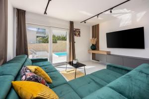 a living room with a green couch and a flat screen tv at Vila Kety in Baška
