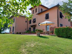 a house with a table and an umbrella in a yard at Agriturismo Corte in Poggio in Stabbia