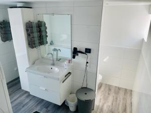 a white bathroom with a sink and a mirror at Apartment Lindenstein in Fritzlar +8 photos