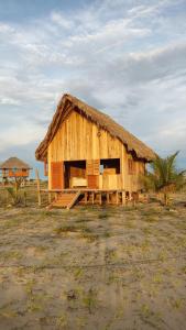 Cabaña de madera con techo de paja en un campo en Pousada Amor Do Arpoador en Tutóia