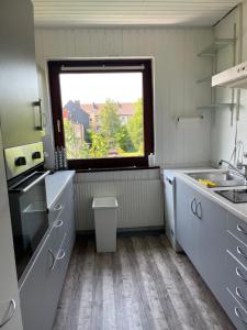 een witte keuken met een raam en een wastafel bij Ferienwohnung in Bremerhaven in Bremerhaven