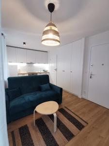 ein Wohnzimmer mit einem blauen Sofa und einem Tisch in der Unterkunft Przytulna kawalerka nad Jeziorem Długim darmowy parking i rowery in Olsztyn