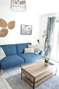 - un canapé bleu dans le salon avec une table basse dans l'établissement Appartement lumineux entre Mer et Campagne, à Pordic