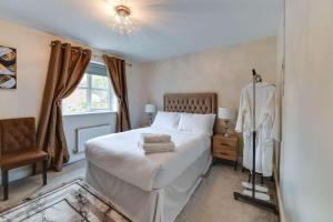 um quarto com uma cama branca, uma cadeira e uma janela em Simitach Serviced Apartments em Middleton