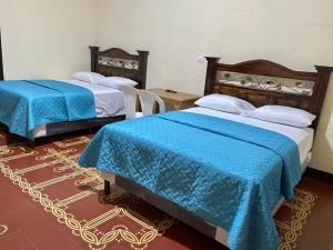 two beds in a room with blue comforter at Hotel Malybu in Guatemala +5 photos