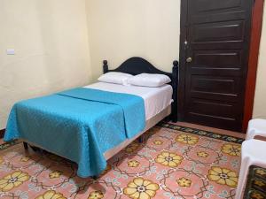 a bedroom with a bed with a blue blanket at Hotel Malybu in Guatemala