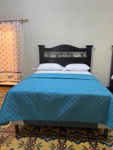 Una cama azul con dos almohadas encima. en Hotel Malybu, en Guatemala