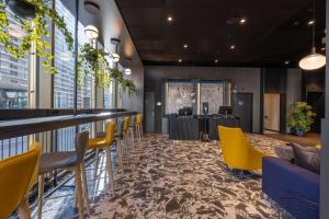 欧普菲康Radisson Hotel & Suites Zurich的一家有黄色椅子和酒吧的餐厅