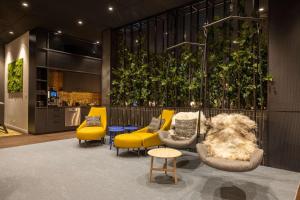 a living room with yellow chairs and a couch at Radisson Hotel & Suites Zurich in Opfikon