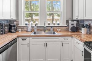 een keuken met witte kasten en een spoelbak bij BeeKeeper's Inn - Beautifully Renovated 1929 Bungalow with 2 Bedrooms on Brick Street near Tampa's Attractions in Tampa