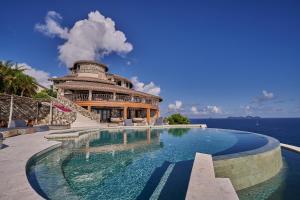 a swimming pool in front of a building next to the ocean at The Aerial, BVI All-Inclusive Private Island in Tortola Island
