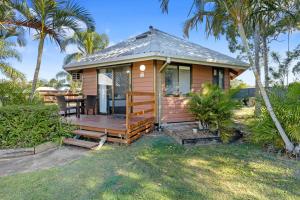 ein kleines Haus mit einer Holzterrasse und Palmen in der Unterkunft Ingenia Holidays Kingscliff in Chinderah