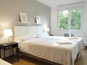a white bedroom with a large bed and two windows at Conde de Vallellano in Córdoba