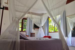 アライアル・ダジュダにあるArraial Praia Hotel Pousadaのベッドルーム(白いカーテン付きの天蓋付きベッド1台付)