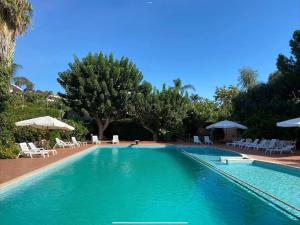 ein großer Pool mit Stühlen und Sonnenschirmen in der Unterkunft [Mare privato] Villa Casamare in Acireale