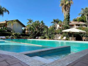 einen Pool mit Sonnenschirm und ein Haus in der Unterkunft [Mare privato] Villa Casamare in Acireale