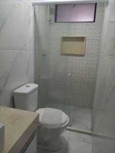 uma casa de banho com um WC e uma cabina de duche em vidro. em Hotel Flat Atlântico em Fortaleza