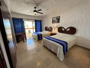 a bedroom with two beds with blue and white sheets at Hotel Quijote Inn in Mazatlán