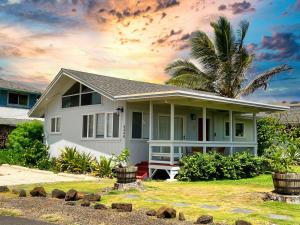 a white house with a palm tree in front of it at OceanFront Kauai - Rhythm TVNC 4288 in Kapaa