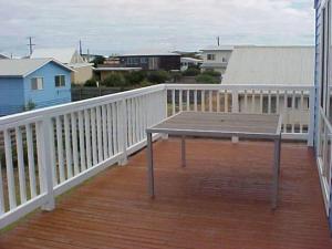 a wooden deck with a bench on a balcony at Sinclair Surfside Stay in Surf Beach