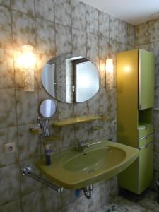 ein Badezimmer mit einem grünen Waschbecken und einem Spiegel in der Unterkunft Tannhäuser Ferienwohnung in Bad Dürrheim