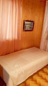 The log house in the village في برامانتا: سرير في غرفة خشبية مع صورة على الحائط