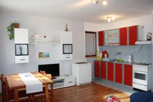 a kitchen with red and white cabinets and a table at Apartment Marija in Poljanak