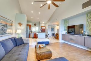 a living room with a blue couch and a kitchen at Luxe Maunalani Resort Condo with Pool and Beach Access in Waikoloa