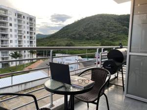 a balcony with a table with a laptop on it at Apto nuevo en Girardot, piscina, BBQ, terraza. in Girardot