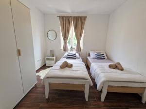 three beds in a room with a window at Apartmani Meri in Privlaka