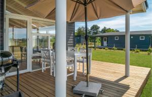 a porch with a table and chairs and an umbrella at Amazing Home In Sams With Kitchen in Nordby