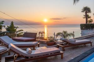 a sunset over the ocean from a resort with lounge chairs at Luxury Taorum villa with spectacular sea views in Taormina in Taormina