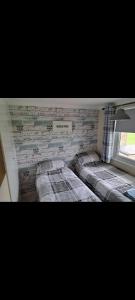 een slaapkamer met drie bedden tegen een bakstenen muur bij California beachhut chalet in Great Yarmouth