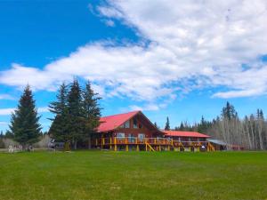 a large house with a red roof on a green field at Cariboo Log Guest House in Lac La Hache