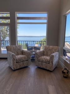 two chairs and a table in a living room with a view at EdgeWater Chemainus in Chemainus