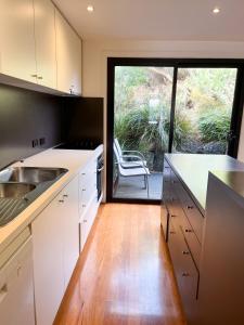 kuchnia z białymi szafkami i przesuwnymi szklanymi drzwiami w obiekcie Southern Ocean Villa 9 w mieście Port Campbell