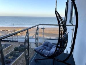 una silla mecedora en un balcón con vistas a la playa en Royal Sands Ramsgate - direct beach access, en Ramsgate