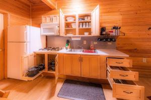 a kitchen with wooden cabinets and a white refrigerator at Cabin #3 Rainbow Trout - Pet Friendly- Sleeps 6 - Playground & Game Room in Payson