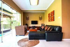 a living room with a black leather couch and a television at Villa LOGAN - KUTA - 5 Bedroom - 3 Bathroom Villa - Great Location in Kuta