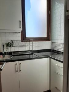 eine Küche mit weißen Schränken, einem Waschbecken und einem Fenster in der Unterkunft Treasure Roses Private Pool Villa in Armamar