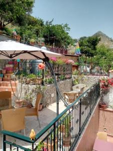 B&B Villa Maria في جيارديني ناكسوس: بلكونة فيها مظلة وطاولة وكراسي