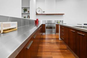 a kitchen with a long counter and a clock on the wall at Ballantyne Abode in Thebarton