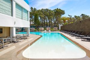 a swimming pool with chairs and a building at Alcazar Hotel & SPA in Monte Gordo