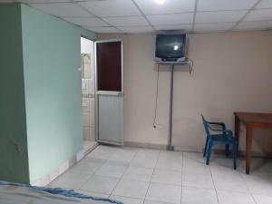 a room with a chair and a television on a wall at Residencial RM in Puerto Francisco de Orellana