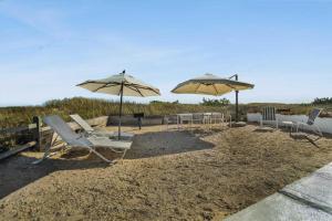 eine Gruppe von Stühlen und Sonnenschirmen am Strand in der Unterkunft Driftwood Resort on the Ocean in Montauk