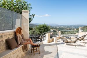 a woman sitting on the ledge of a building at Prinus Country Retreat Apokoronas, heated pool, 13km from the sea in Embrósneros